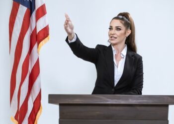Melania Trump speaking at a podium during a White House event, expressing denial of Epstein ties.