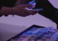 A person examining digital currency tokens with a warning sign about counterfeit risks.