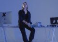 A hacker at a computer, with cryptocurrency charts and dollar signs in the background.