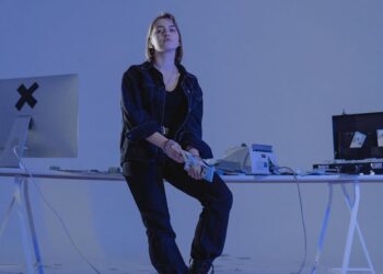 A hacker at a computer, with cryptocurrency charts and dollar signs in the background.