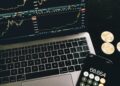 Bitcoin coins arranged beside a calculator and financial graphs, symbolizing ETF investments.