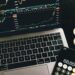 Bitcoin coins arranged beside a calculator and financial graphs, symbolizing ETF investments.