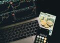 Wealthy investor reviewing cryptocurrency assets on a laptop with financial charts displayed.