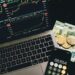 Wealthy investor reviewing cryptocurrency assets on a laptop with financial charts displayed.