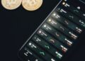 A warning sign with a phishing hook and a smartphone displaying cryptocurrency apps.
