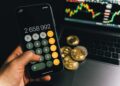 A close-up of a cryptocurrency coin surrounded by financial documents and a calculator.