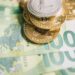 Euro banknotes and cryptocurrency coins on a financial report background, symbolizing regulation.