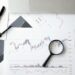 A gavel rests on financial documents with charts, symbolizing regulatory challenges in prediction markets.