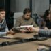 Business meeting with individuals discussing financial documents and cryptocurrency regulations.