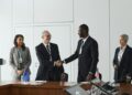 Executives from Startale Group and Sunnyside Labs shake hands in a tech conference setting.
