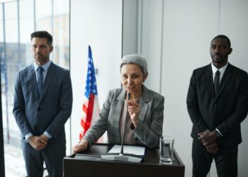 Three politicians at a press conference, discussing regulations and insider trading issues.