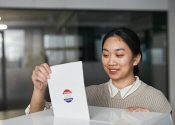 A woman in business attire exits a government building, carrying documents related to voter data.