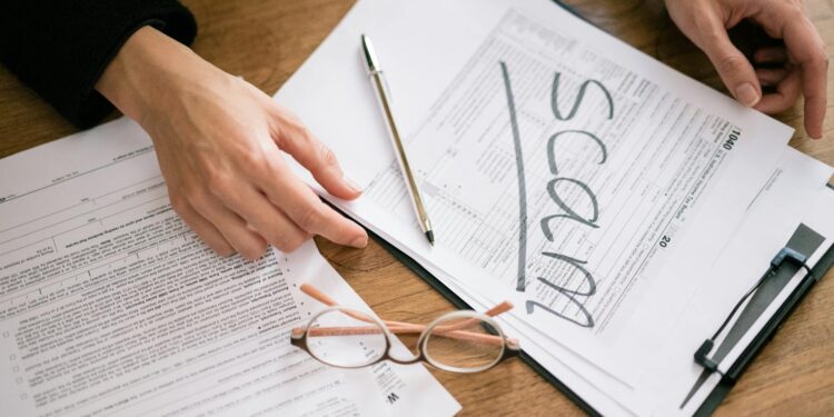 Financial advisor reviewing crypto tax forms with a calculator and laptop.