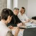 Small crypto firm employees discussing compliance documents and financial regulations.