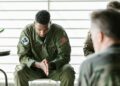 Uniformed soldier in handcuffs at a military base, reflecting insider trading concerns.