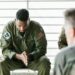 Uniformed soldier in handcuffs at a military base, reflecting insider trading concerns.