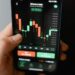 A close-up of a smartphone displaying call logs and cryptocurrency graphs.