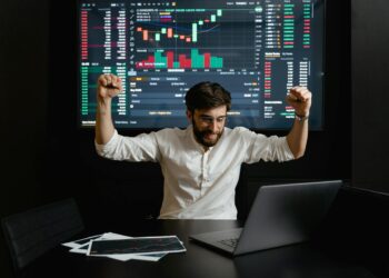 A diverse group of investors celebrating a financial milestone with charts and laptops.
