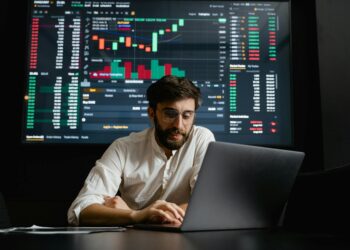 A trader analyzes digital currencies on a laptop with charts depicting Polymarket's new stablecoin.