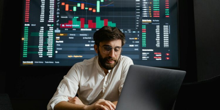 A trader analyzes digital currencies on a laptop with charts depicting Polymarket's new stablecoin.
