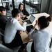Employees in an office discussing restructuring and job cuts at a tech startup.