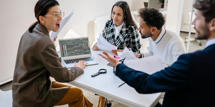 A group of employees in an office setting discussing financial strategies and layoffs.