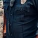 An ICE agent in uniform stands outside a building during a law enforcement operation.