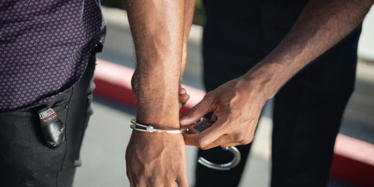 Li Xiong in handcuffs being escorted by authorities, highlighting extradition in fraud case.