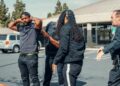 Police arresting a cryptocurrency founder outside a corporate building amidst news coverage.