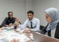 Employees in a meeting room appear concerned as Meta announces significant layoffs.