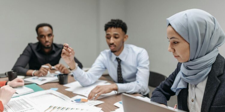 Employees in a meeting room appear concerned as Meta announces significant layoffs.