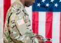US soldier in military uniform with financial charts and Polymarket logo in the background.