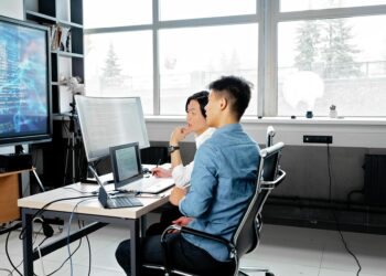 Developers collaborating on a Bitcoin project with code and digital screens in a tech workspace.