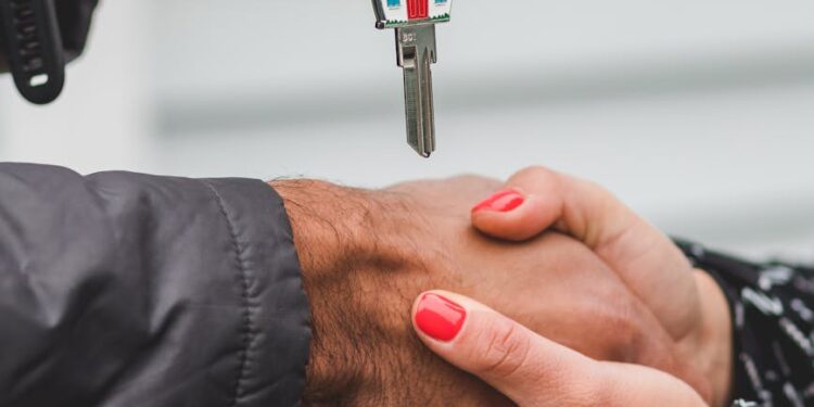 Hands shaking over a contract, cryptocurrency symbols in the background, symbolizing a real estate deal.