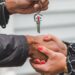 Hands shaking over a contract, cryptocurrency symbols in the background, symbolizing a real estate deal.