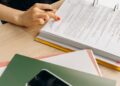 A person examines cryptocurrency symbols and regulatory documents on a desk.