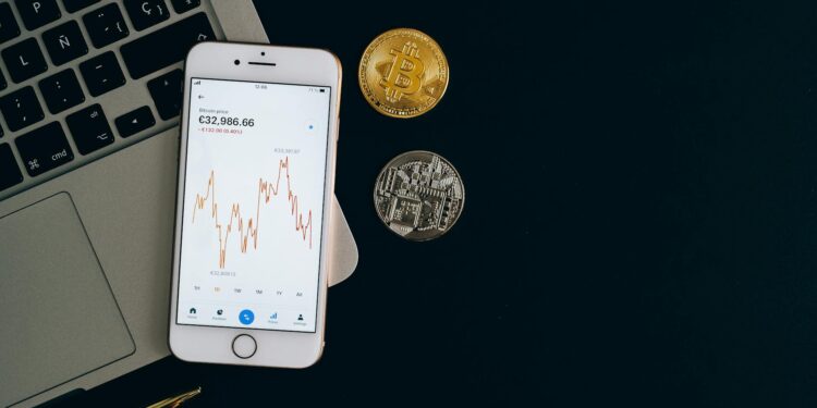 A smartphone displaying a cryptocurrency wallet app with declining market graphs.