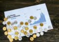 Bitcoin coins being sold with financial charts and debt repayment documents in the background.