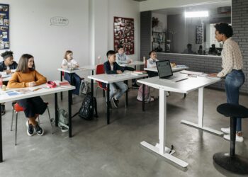 Bitcoin logo superimposed on a classroom setting with students and teachers engaging in learning.