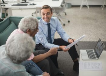 A financial advisor discusses cryptocurrency with clients in a modern office setting.