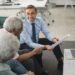 A financial advisor discusses cryptocurrency with clients in a modern office setting.