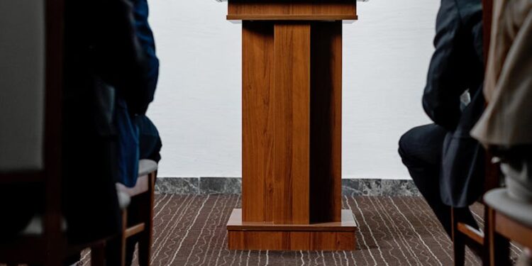Kash Patel speaking at a podium during a press conference on his lawsuit against The Atlantic.