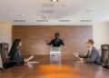 Politician discussing AI dividend proposal with displaced workers in a conference setting.