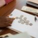 Hands counting cryptocurrency coins with a financial document and calculator in the background.