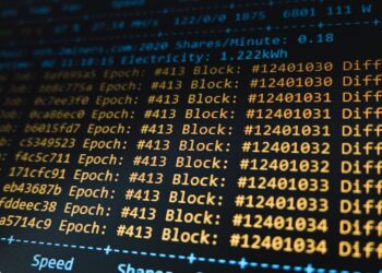 A computer screen displays blockchain code while Bitcoin symbols surround it.