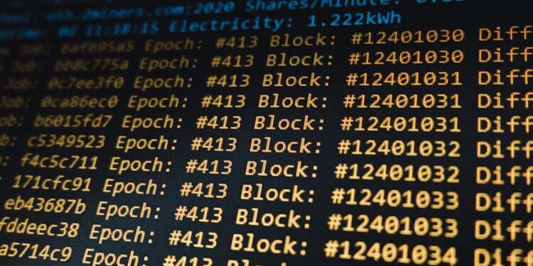 A computer screen displays blockchain code while Bitcoin symbols surround it.