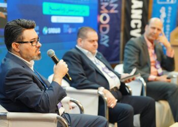 Two men on stage discussing cryptocurrency at a conference in Miami.