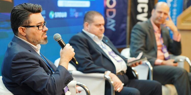 Two men on stage discussing cryptocurrency at a conference in Miami.