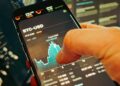 A man checks cryptocurrency prices on a smartphone amidst financial news articles.