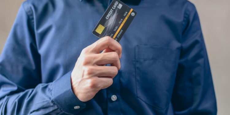 A person holding a debit card labeled "MoonAgents" with cryptocurrency symbols in the background.